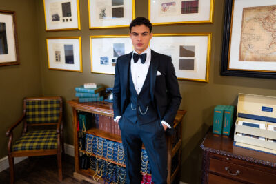 Slim fit classic black dinner suit in light weight, 100% wool. 3 piece dinner suit with traditional black tux jacket, classic black dinner suit trousers and black low cut V shape waistcoat. Features a slim fit 1 button black dinner jacket with classic black satin peak lapel. Worn with white studded dress shirt with French cuff shirt and large tom ford style bow tie and white pocket square.